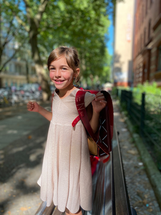 Ein Mädchen mit einem roten Schulranzen trägt ein Sommerkleid von vincente aus Tencel/Lyocell gestrickt in Beige