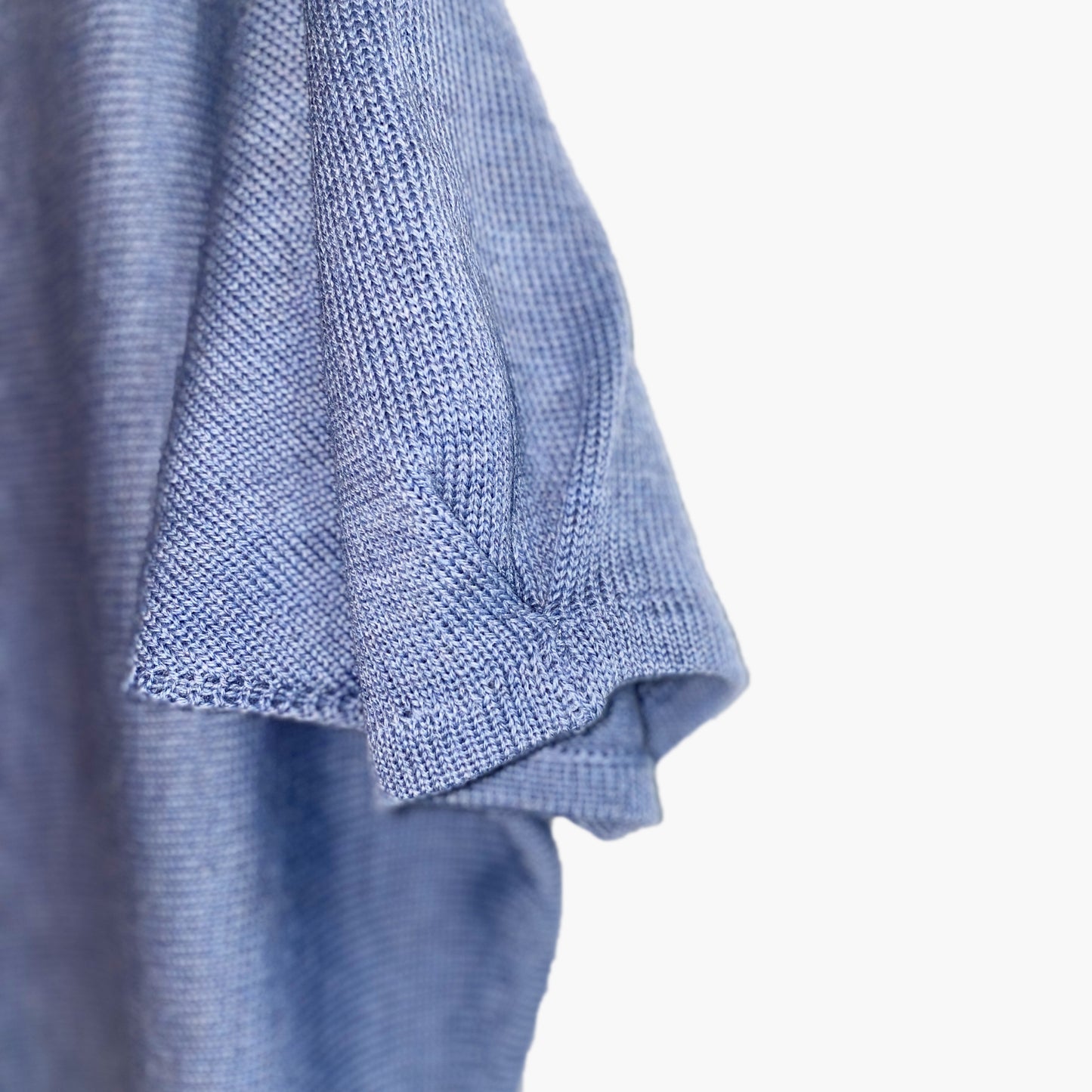 Detailansicht der Ärmelfalte des quer gestrickten Pullovers. Der Pulli ist Graublau.