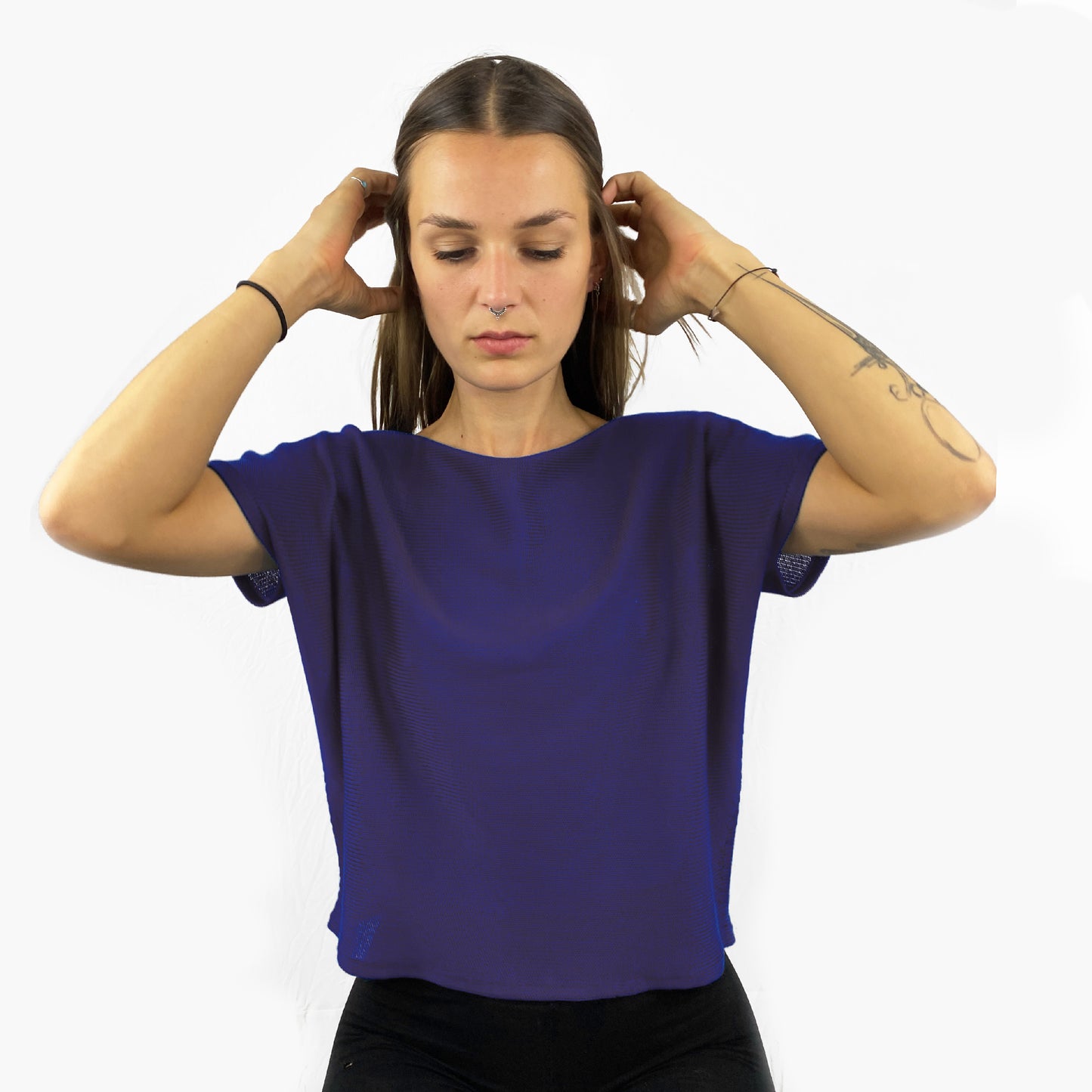 Unser Model mit glatten, Langem, braunem Haar und Taatoos (Schmetterling, Scorpion) auf dem Arm trägt ein seidig gänzendes T-shirt von vincente. Das Shirt ist aus Tencel/Lyocell gestrickt hat eine kleine Falte an dem kurzen Arm und ist dunkel Blau.