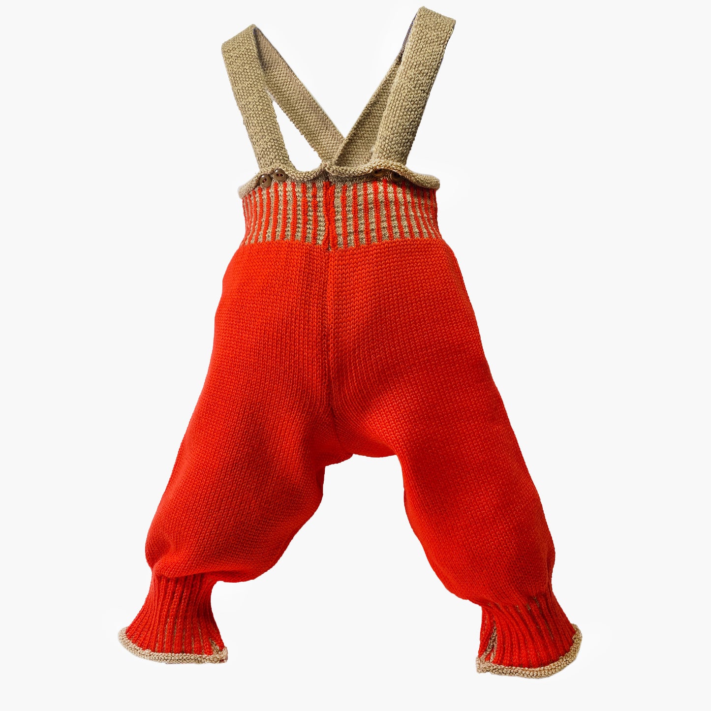 Woll-Hose, Salopette aus Bio-Merinowolle von vincente gestrickt. Sie ist Orangerot mit Karamelfarbenen Hosenträgern und Karamelfarbenen Streifen im enganliegenden Bündchen. Die Knöpfe sind Beige und mit Roten Garn angenäht