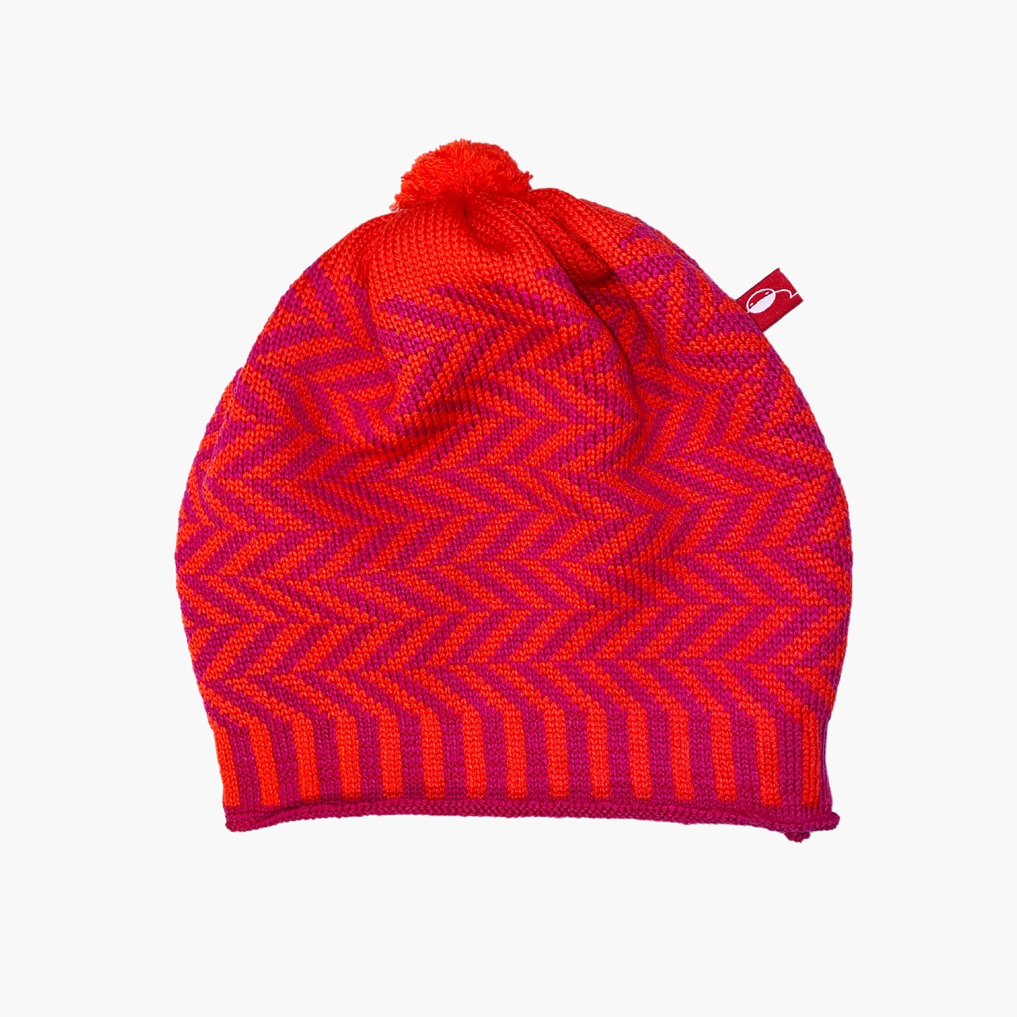Orangerote/Pinkfarbene Beanie-Mütze aus Merinowolle mit längs gestreiften elastischem Bündchen. Die Mütze ist im klassichem Fischgrätmuster gestrickt und hat eine kleine unauffällige Bommel.