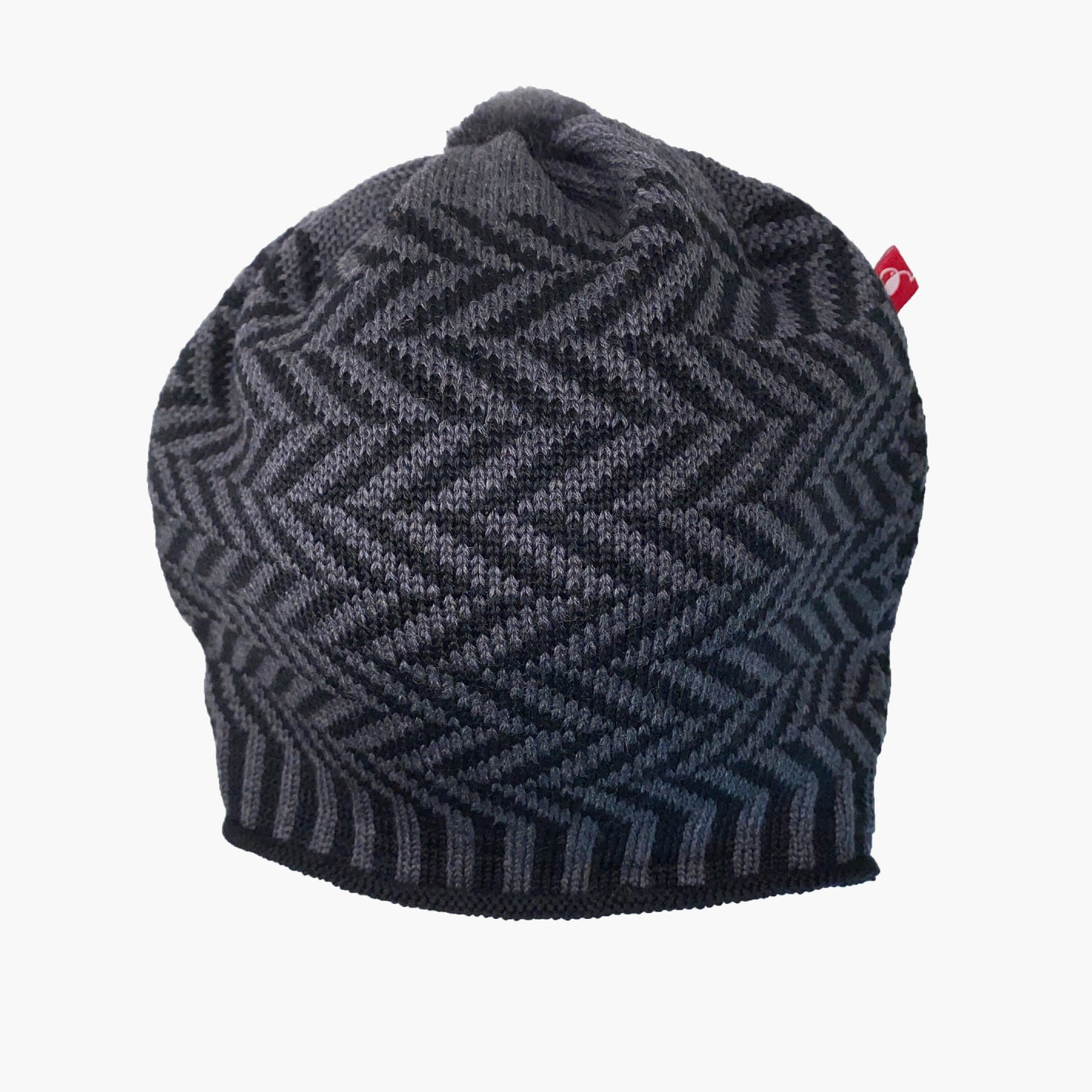 Schwarz/Graue Beanie-Mütze aus Merinowolle mit längs gestreiften elastischem Bündchen. Die Mütze ist im klassichem Fischgrätmuster gestrickt und hat eine kleine unauffällige Bommel.