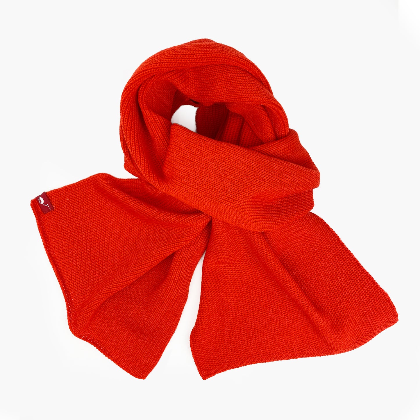 Orange-roter, gestrickter Schal im Fangpatentmuster. Eine Seite sieht glatt rechts gestrickt, die andere Seite sieht aus wie minikleine Muscheln oder Punkte. Der Wollschal ist zu einem Haufen drapiert, so sieht man den weichen Fall.