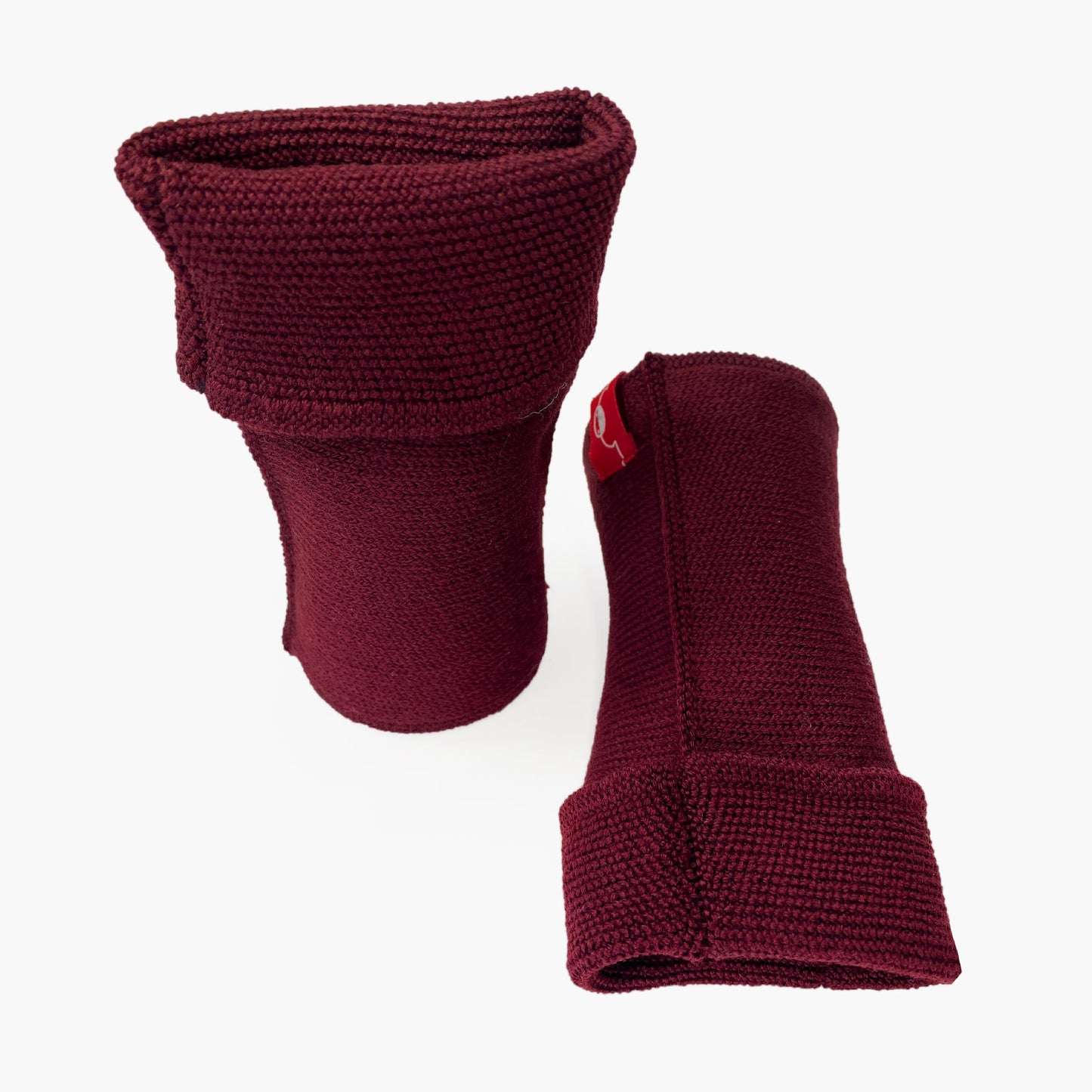 Bordeauxfarbene, aufrecht stehende Armstulpen. Man sieht das außenliegende Glatt Rechts Muster. Innen sind die Stulpen in einem Feinen Knötchenmuster gestrickt, man kann sie auch Innsideout tragen