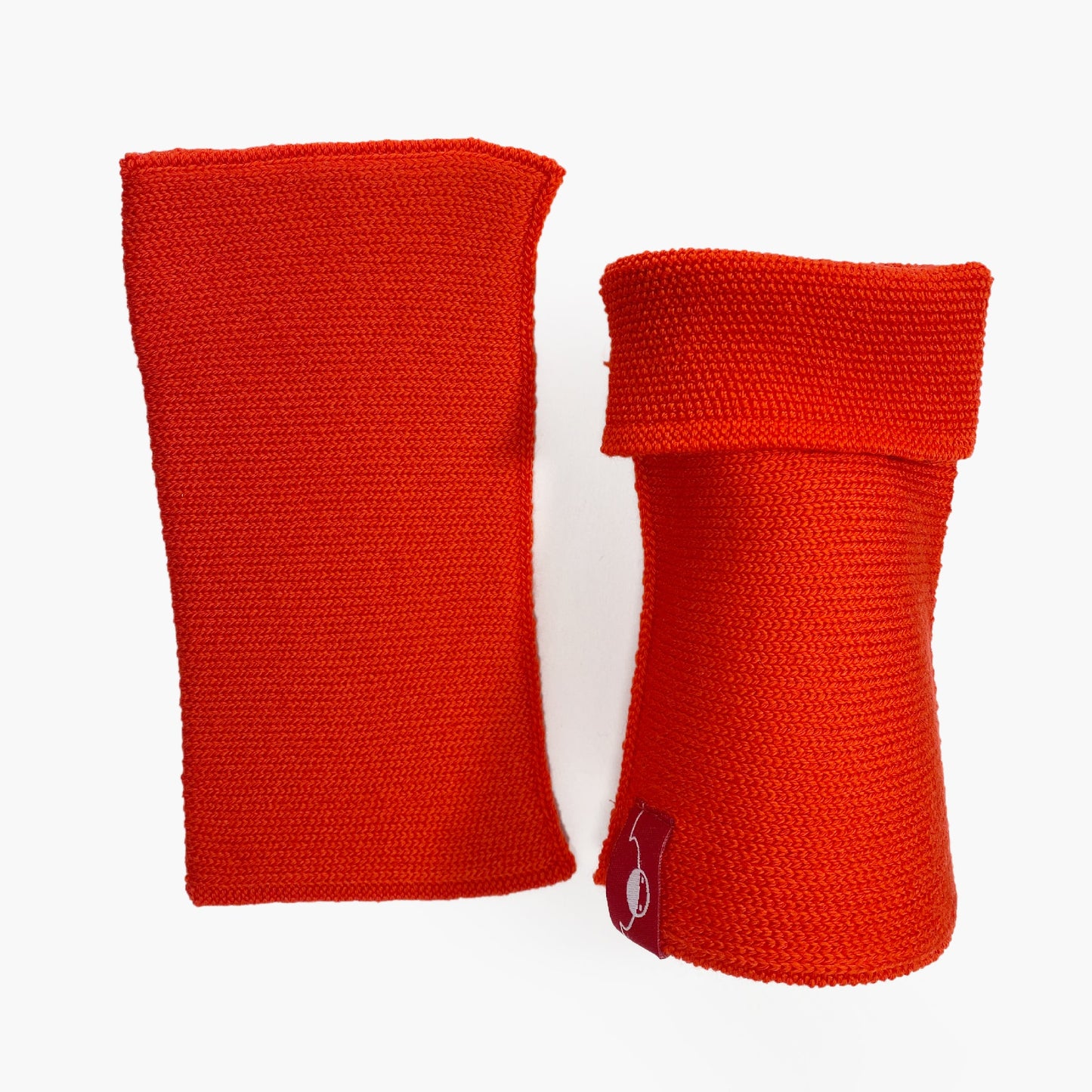 Orangerote, aufrecht stehende Armstulpen. Man sieht das außenliegende Glatt Rechts Muster. Innen sind die Stulpen in einem Feinen Knötchenmuster gestrickt, man kann sie auch Innsideout tragen
