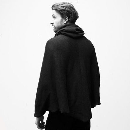 Ein junger Mann mit Don Quichotte Bart trägt das schwarze gestrickte Capes.