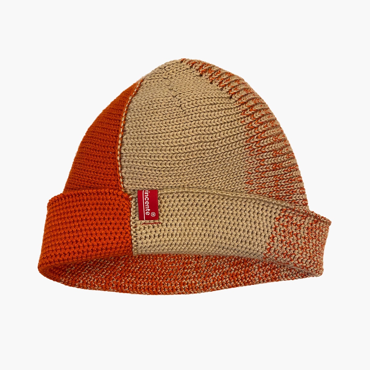 Karamel/Orange farbene Beanie. Der Rand ist umgeschlagen, wie bei einer Dockermütze. Die Mütze hat einen Farbverlauf, der sich im Kreis wie folgt verhält: ein Stück Karamel-farben ein Stück Orange Dazwischen michen sich die beiden Farben im Farbverlauf von Karamel mit etwas Orange dann etwas mehr Orange usw.