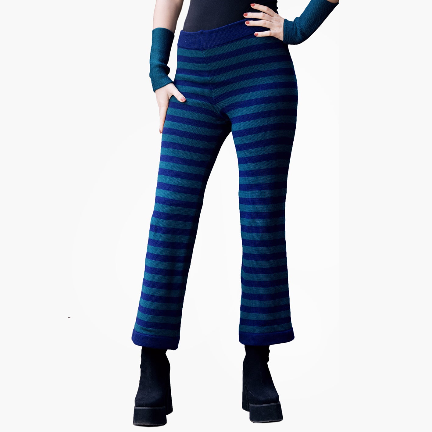 Eine Junge Frau in schwarzen Plateauxschuhen trägt eine Gestreife Wollhose. Die Hose hat ca 3cm breite Ringel Petrol und Royalblau. Man Sieht Sie von der TAille abwärts.