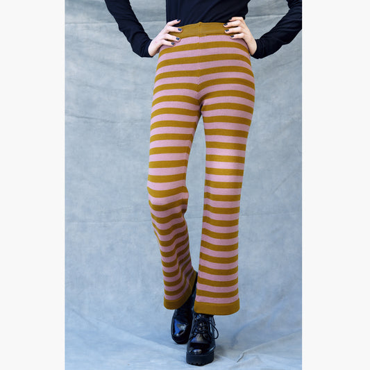 Eine Junge Frau in schwarzen Plateauxschuhen trägt eine Gestreife Wollhose. Die Hose hat ca 3cm breite Ringel in Bronce und Rosenholz. Man Sieht Sie von der TAille abwärts.