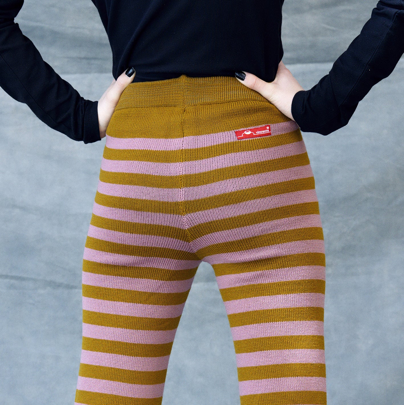 Rückansicht einer Frau die eine Gestreife Wollhose trägt. Die Hose hat ca 3cm breite Ringel in Bronce und Rosenholz.