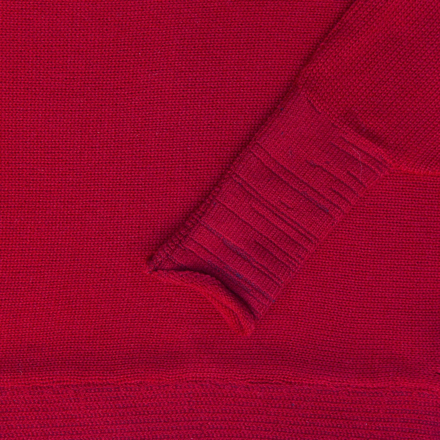 Detailansicht des Roteb gestrickten Pullover mit angeschnittenen Ärmeln. Man sieht das Ärmelbündchen.