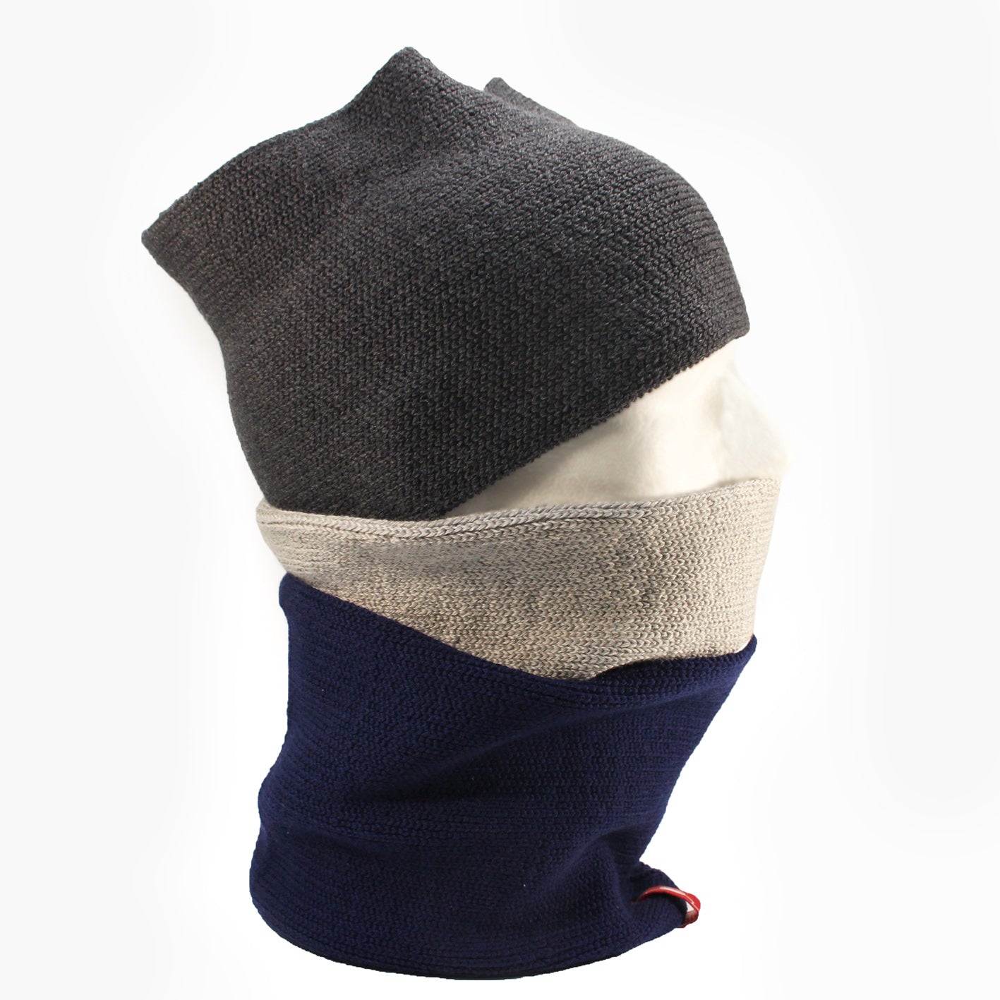 Auf einen Männerpuppenkopf sind 3 gestrickte Loops trapiert. Ein dunkelgrauer über die Stirn ein Silbergrauer über den Mund und ein Royalblauer über den Hals.