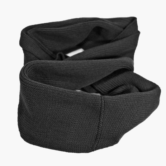 Schwarzer, gestrickter Loop im Fangpatentmuster. Eine Seite sieht glatt rechts gestrickt, die andere Seite im feinen Muschelmuster. Der Schal ist auf zu einem Haufen drapiert ist, so sieht man den weichen Fall des Wollschals sieht.