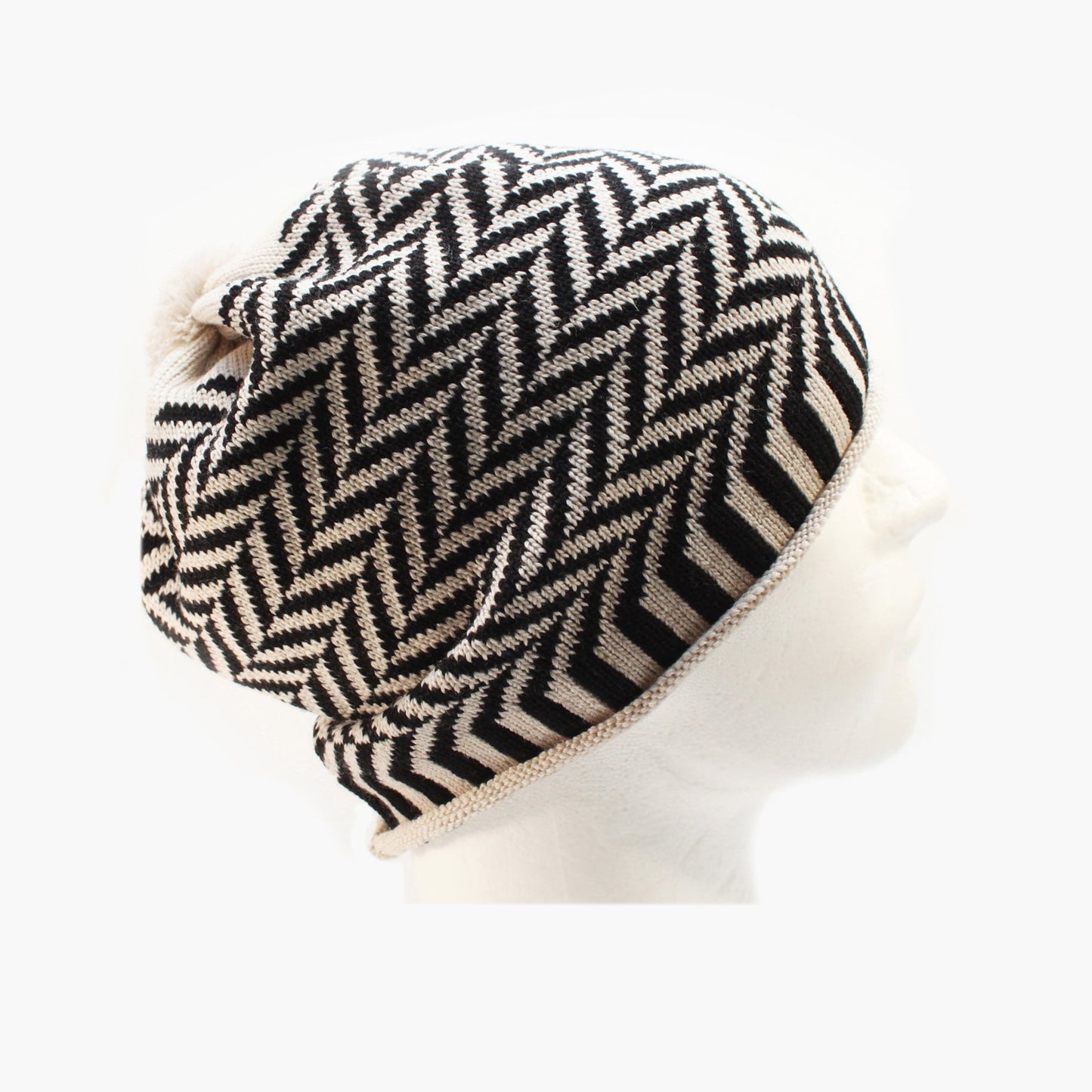 Schwarz/Weiße Beanie-Mütze aus Merinowolle mit längs gestreiften elastischem Bündchen. Die Mütze ist im klassichem Fischgrätmuster gestrickt und hat eine kleine unauffällige Bommel.