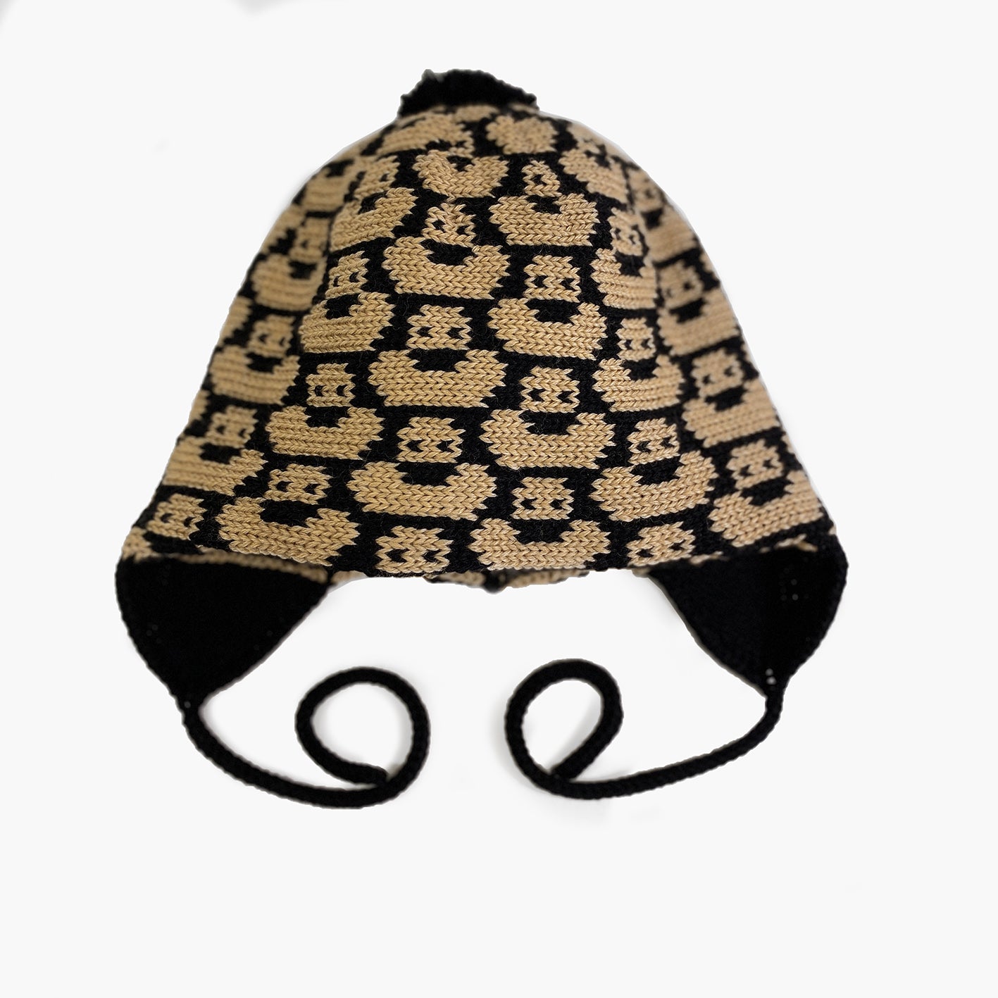 Schwarz/Karamalfarbene Mütze für Babies und Kinder mit einem fortlaufenden Muster mit kleinen Enten. Die Babymütze hat eine Bommel und angestrickte Ohrläppchen mit Bändern zum festbinden. Sie ist aufwendig der Kopfform nachgestrickt und paßt sich sehr gut an. Das rote Label mit der kleinen Ente ist hinten angenäht.