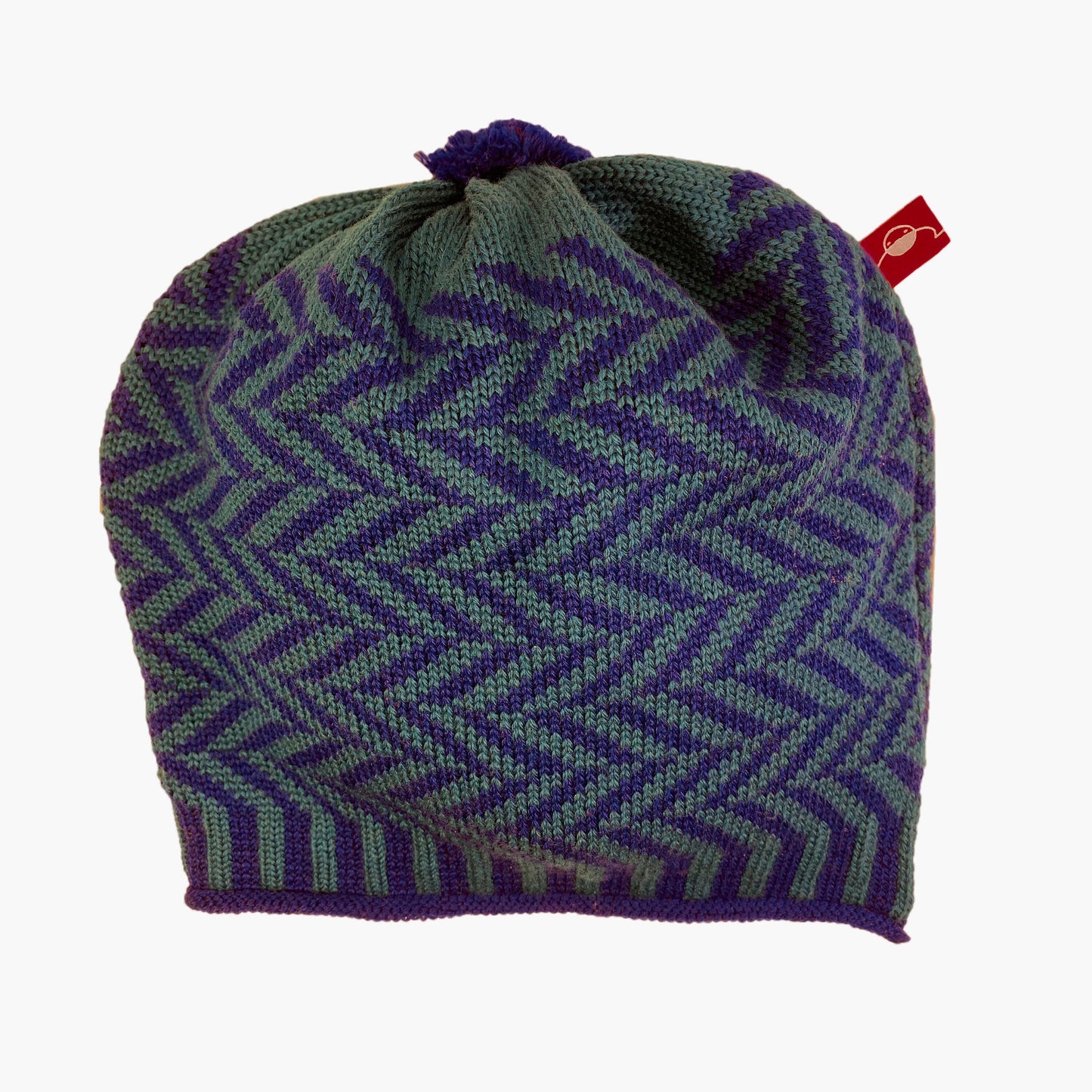 Petrol/Royalblaue Beanie-Mütze aus Merinowolle mit längs gestreiften elastischem Bündchen. Die Mütze ist im klassichem Fischgrätmuster gestrickt und hat eine kleine unauffällige Bommel.