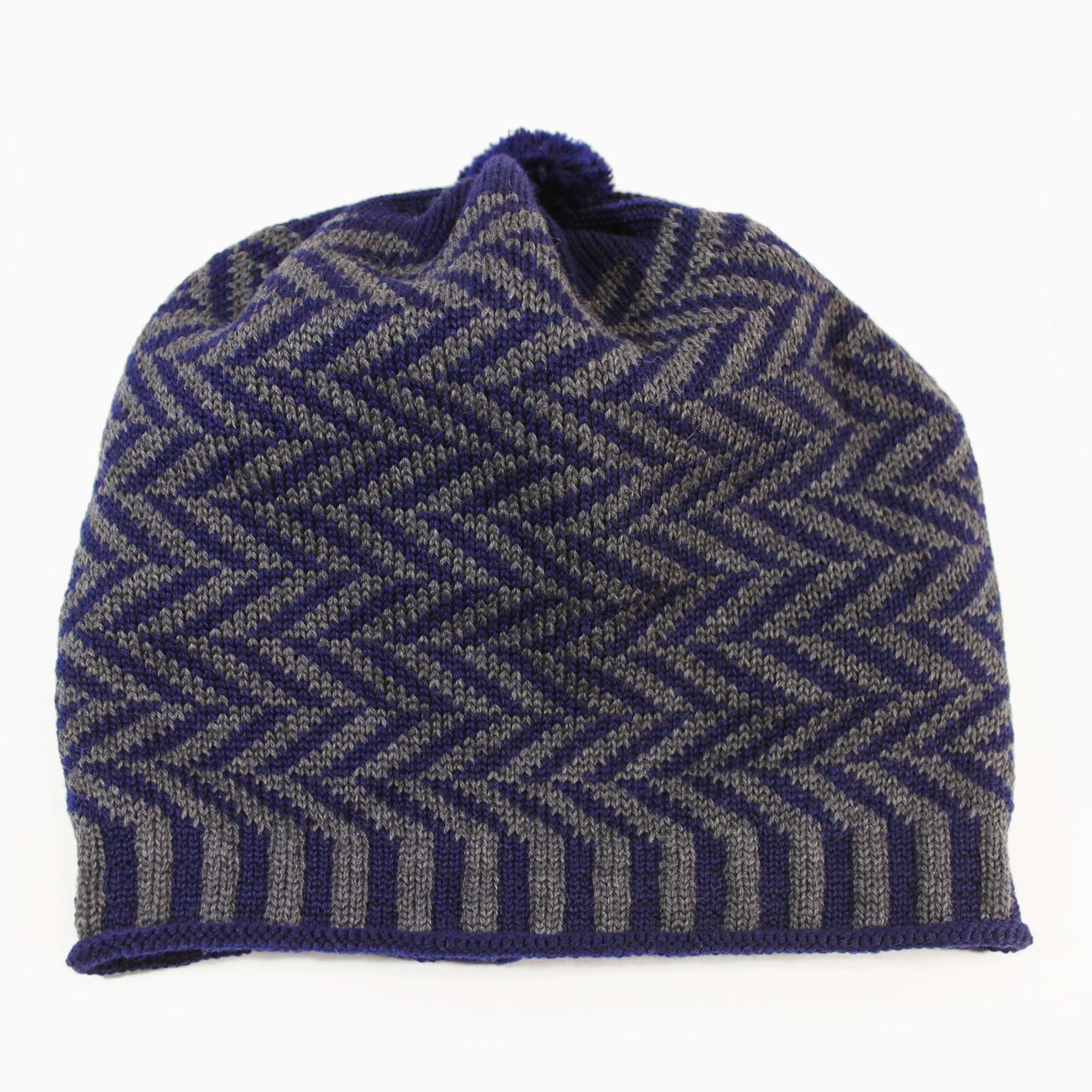 Dunkelgrau/Royalblaue Beanie-Mütze aus Merinowolle mit längs gestreiften elastischem Bündchen. Die Mütze ist im klassichem Fischgrätmuster gestrickt und hat eine kleine unauffällige Bommel.