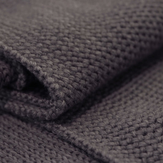 Detailansicht eines Grauen gestrickten Schals im Fangpatentmuster. Eine Seite sieht glatt rechts gestrickt, die andere Seite sieht aus wie minikleine Muscheln oder Punkte.