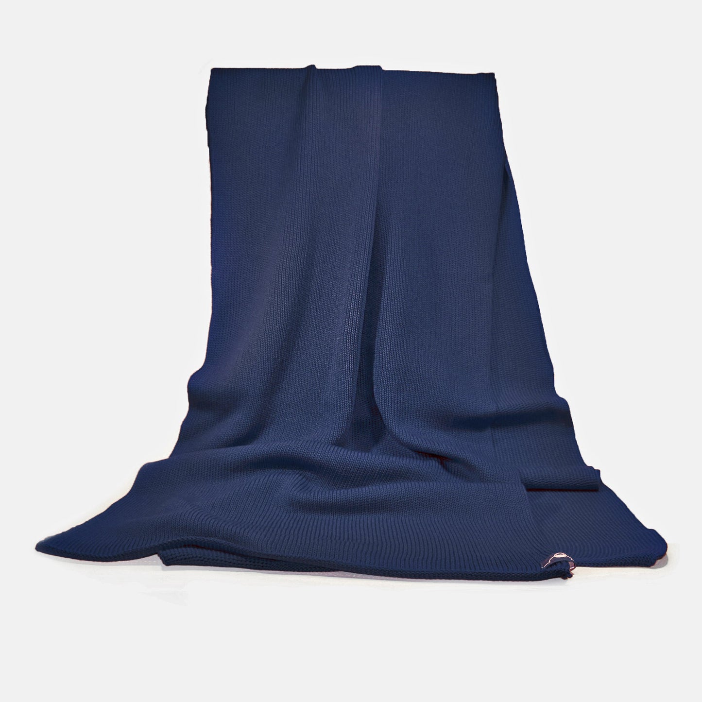 Dunkelblauer, gestrickter Schal im Fangpatentmuster. Eine Seite sieht glatt rechts gestrickt, die andere Seite sieht aus wie minikleine Muscheln oder Punkte. Der Wollschal ist zu einem Haufen drapiert, so sieht man den weichen Fall.