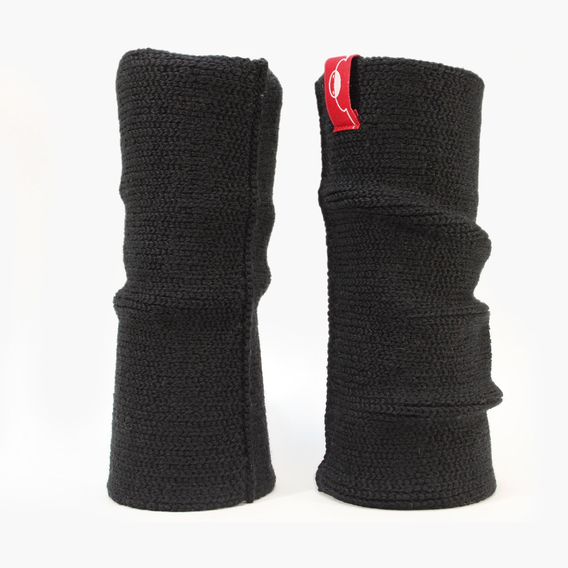 Schwarze aufrecht stehende Armstulpen. Man sieht das außenliegende Glatt Rechts Muster. Innen sind die Stulpen in einem Feinen Knötchen-Muster gestrickt, man kann sie auch Innside-out tragen