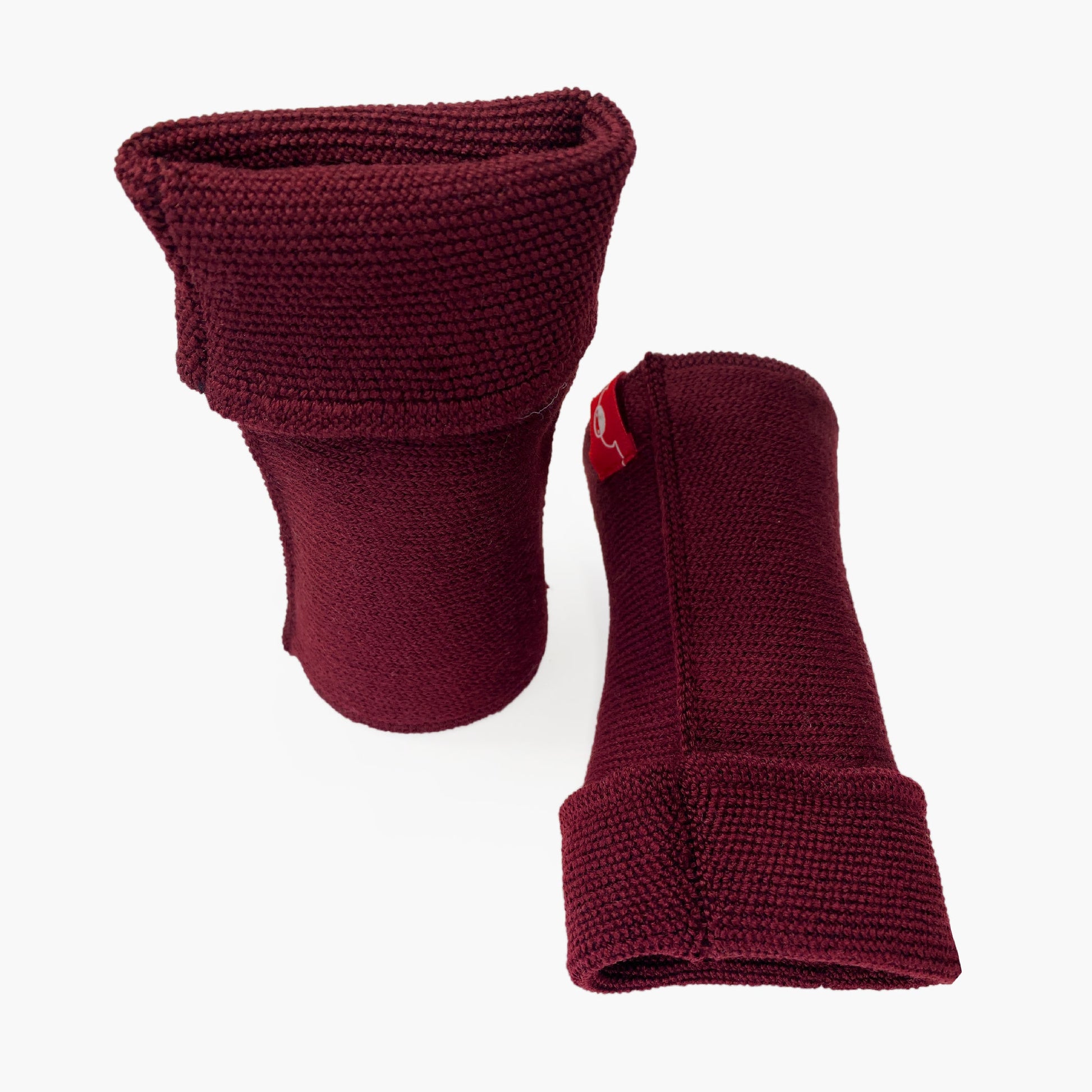 Bordeauxfarbene, aufrecht stehende Armstulpen. Man sieht das außenliegende Glatt Rechts Muster. Innen sind die Stulpen in einem Feinen Knötchenmuster gestrickt, man kann sie auch Innsideout tragen