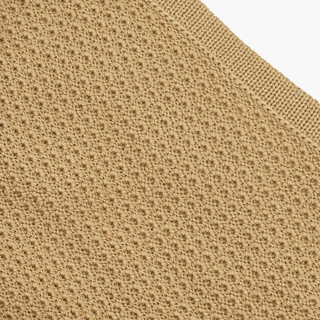 Closeup der Strickstrucktur der Rückseite der gestrickten Baydecke. Das Fangpatentmuster sieht wie kleine Bögen aus die sich endlos wiederholen. Die Wolle ist Karamelfarben.