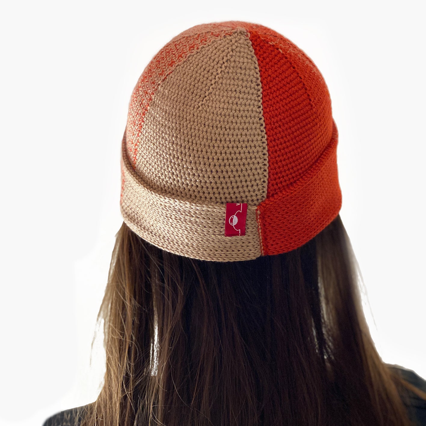 Eine Frau trägt eine Beanie-Mütze, mit Farbverlauf der sich in verschiedenen Karamel und Orange Kobinationen ändert.