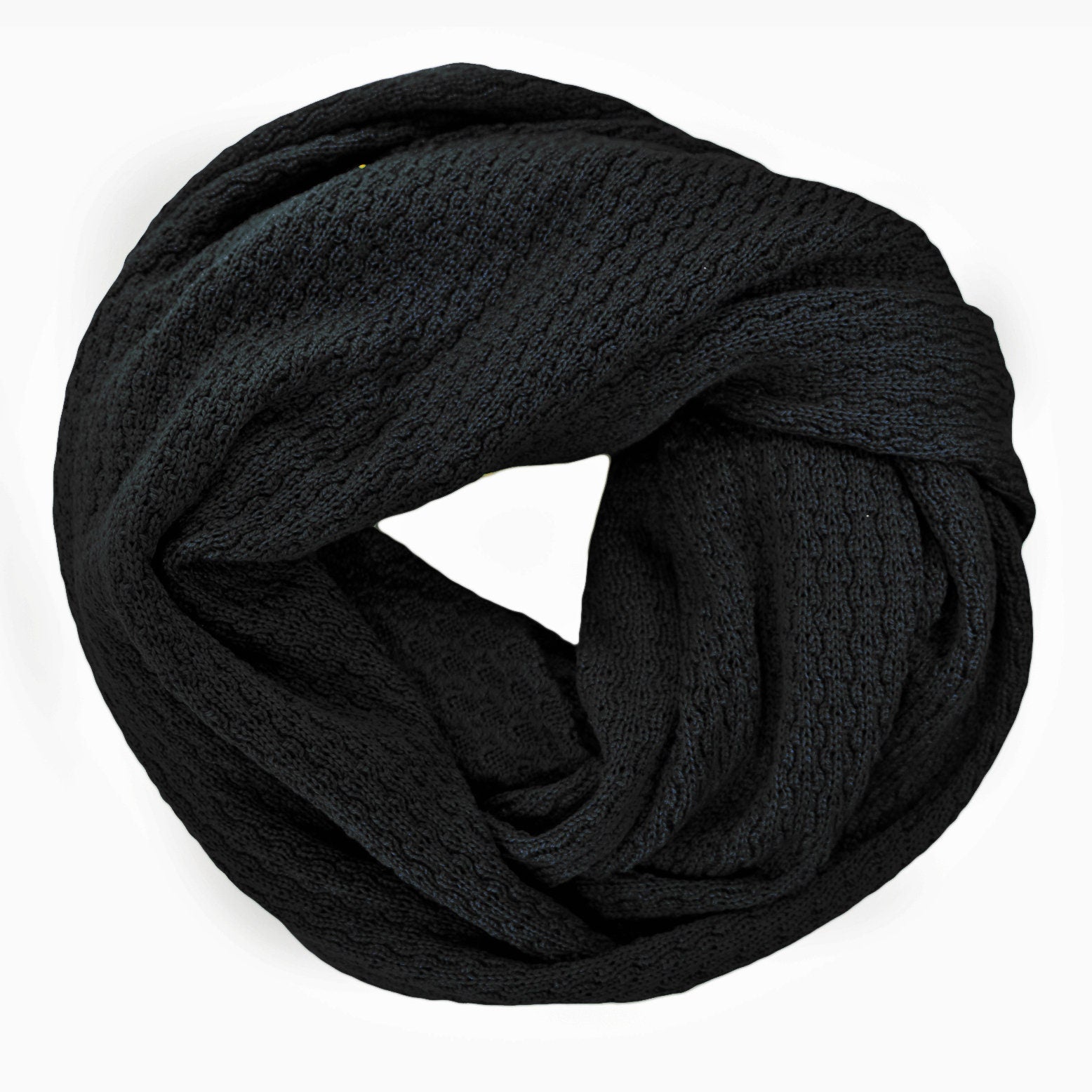 Schwarzer, gestrickter Loop im Fangpatentmuster. Eine Seite sieht glatt rechts mit kleinen Wellen gestrickt aus, die andere Seite sieht aus wie kleine Muscheln. Der Wollschal ist zu einem Haufen drapiert, so sieht man den weichen Fall.