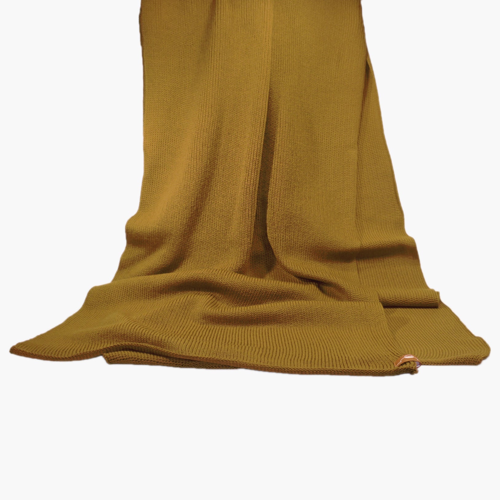 Bronce-Farbener, gestrickter Schal im Fangpatentmuster. Eine Seite sieht glatt rechts gestrickt, die andere Seite sieht aus wie minikleine Muscheln oder Punkte. Der Wollschal ist zu einem Haufen drapiert, so sieht man den weichen Fall.