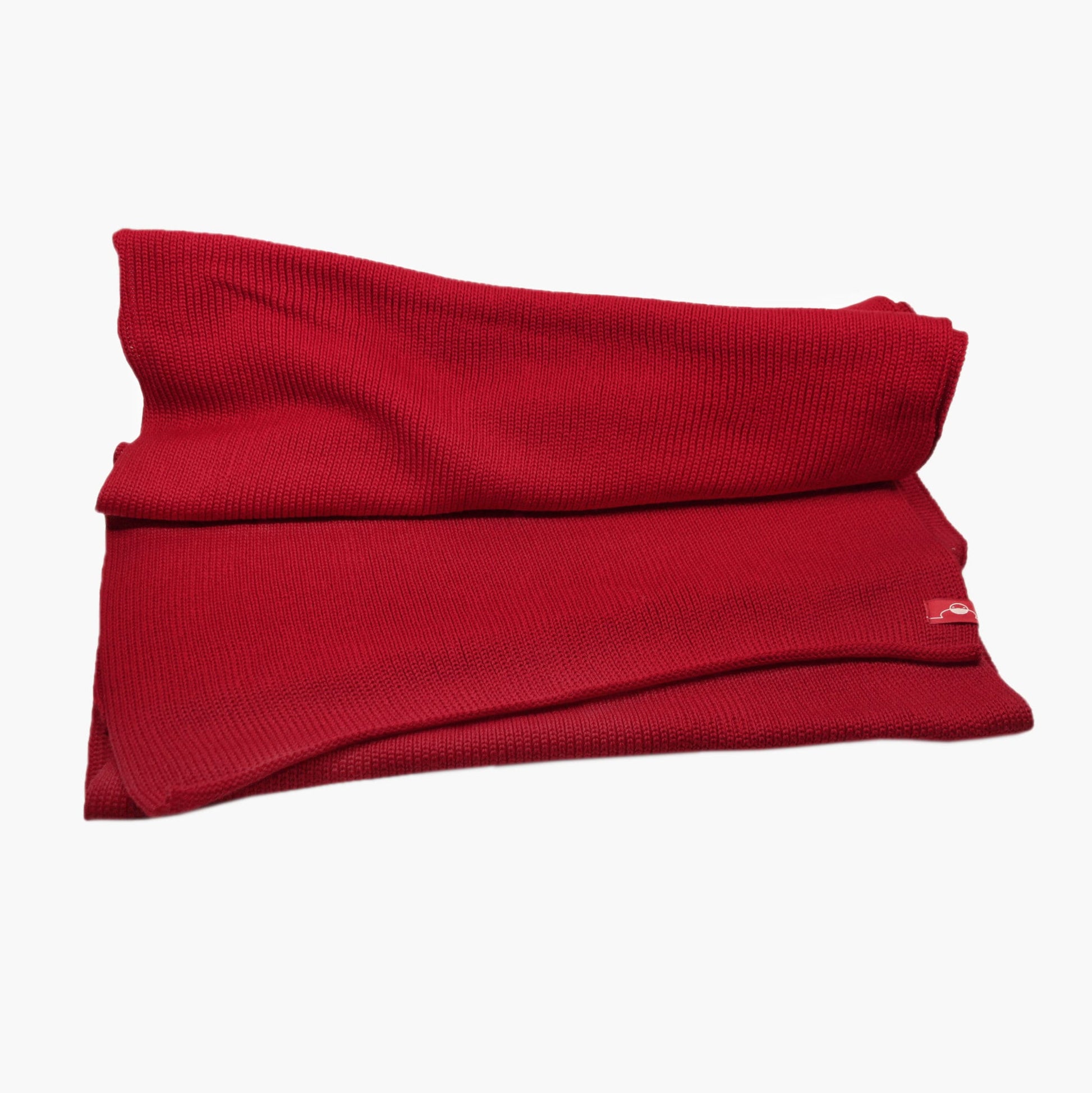 Roter, gestrickter Schal im Fangpatentmuster. Eine Seite sieht glatt rechts gestrickt, die andere Seite sieht aus wie minikleine Muscheln oder Punkte. Der Wollschal ist zu einem Haufen drapiert, so sieht man den weichen Fall.
